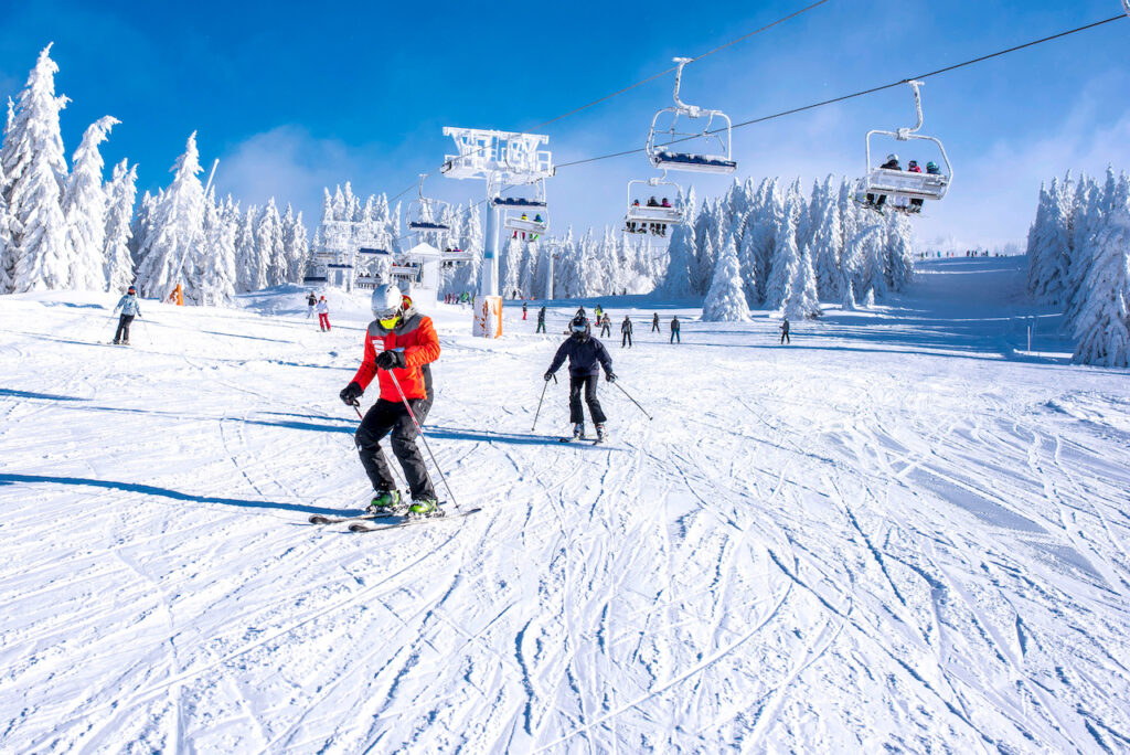 ľudia lyžujúci na upravenom lyžiarskom svahu v stredisku